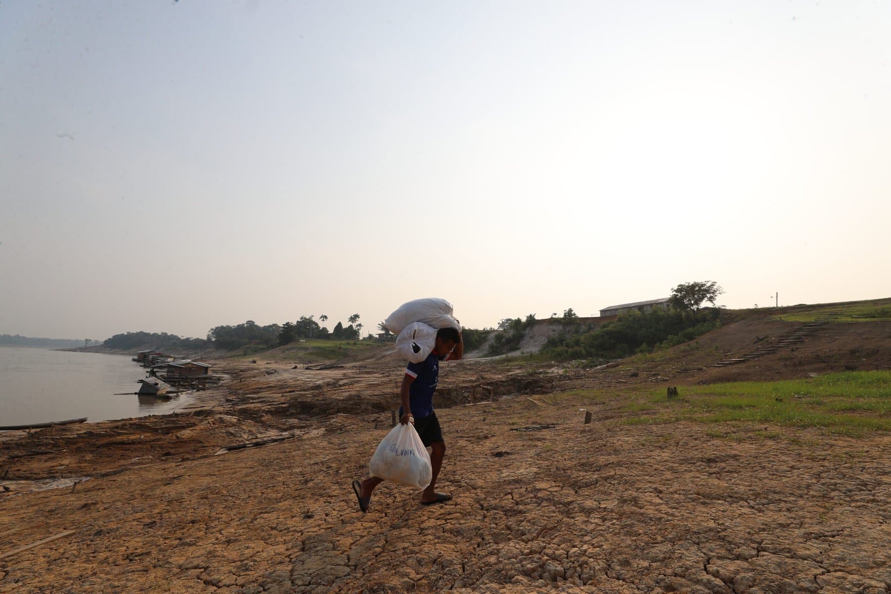 Mulher indígena observa o horizonte em comunidade às margens de rio na Amazônia.