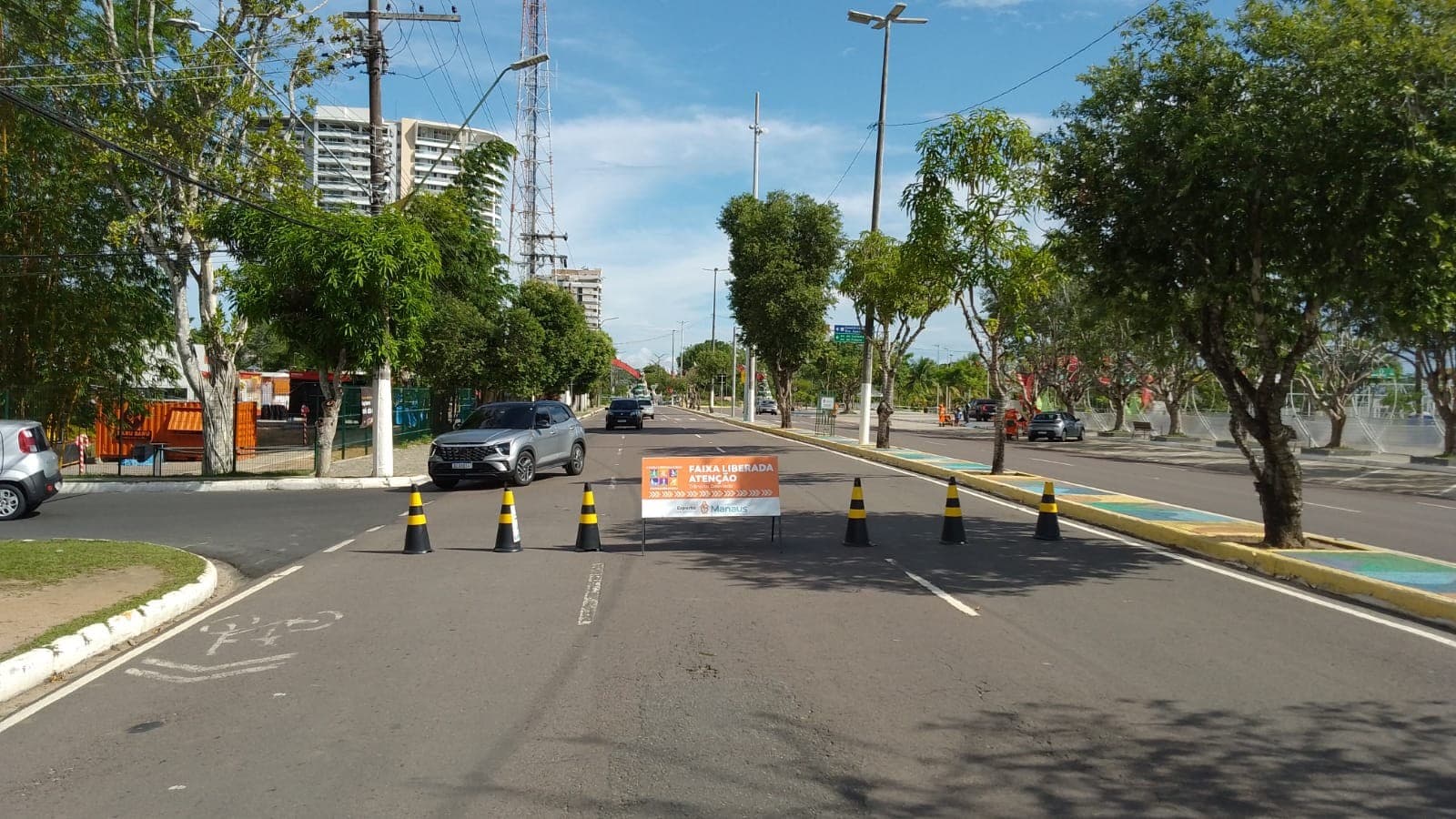 Participantes de corrida de rua cruzam avenida em Manaus durante competição esportiva ao amanhecer.