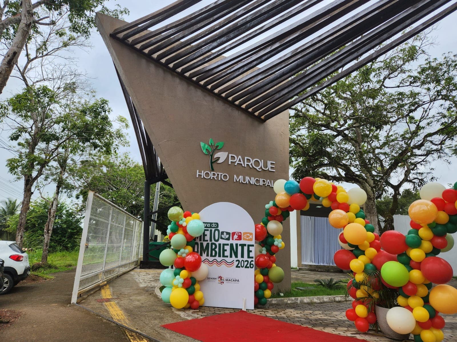 Trilha de terra cercada por vegetação densa leva ao orquidário no Parque Horto Municipal.