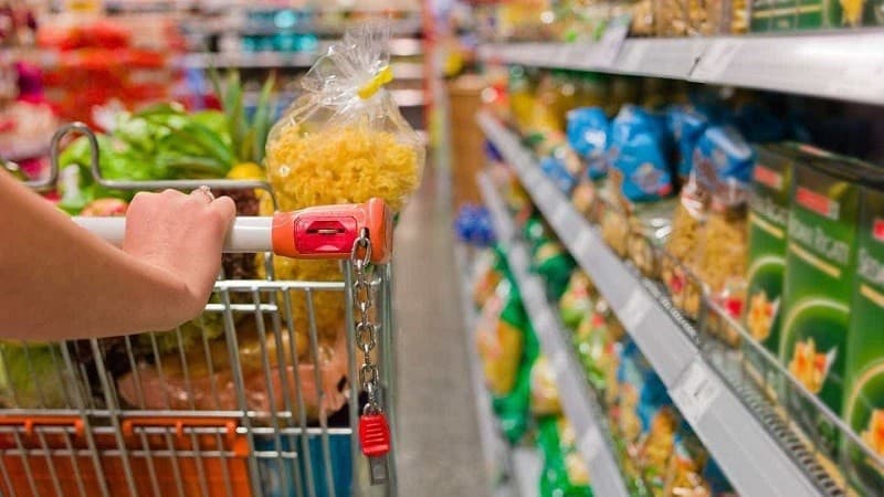 Feirante organiza hortaliças e legumes em banca de mercado municipal em Manaus.