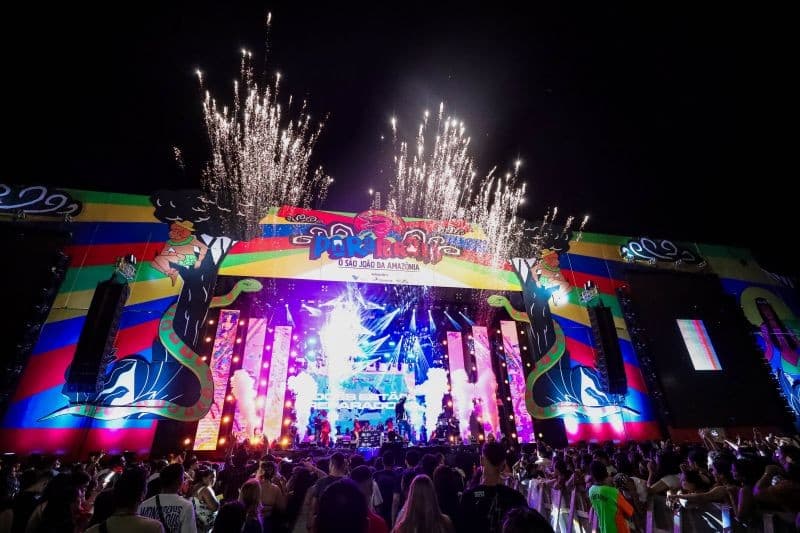 Bandarilhas coloridas iluminam estrutura de palco montada em estacionamento para festa junina em Belém.
