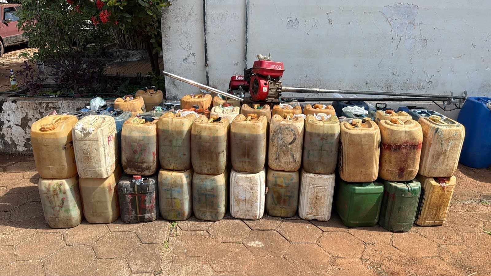 Galões de combustível amontoados em embarcações às margens do Rio Mamoré durante ação da Polícia Federal.