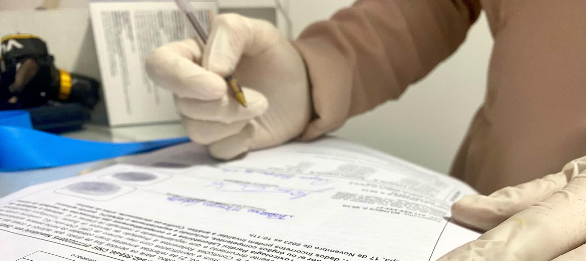 Fila de espera no DETRAN-AP e um formulário de exame toxicológico sobre mesa.