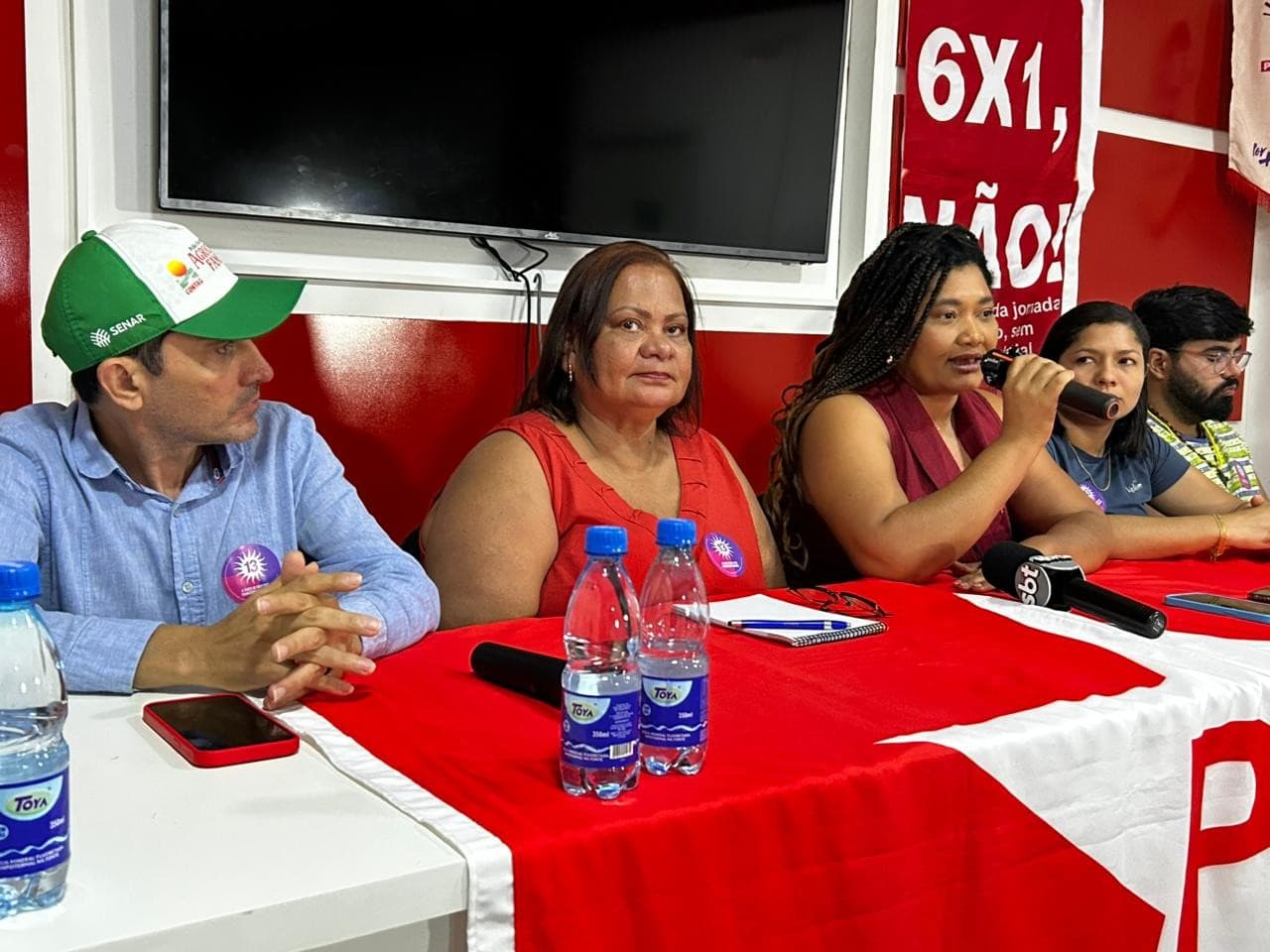 Documento de registro de candidatura sobre mesa com microfone do Tribunal Regional Eleitoral.