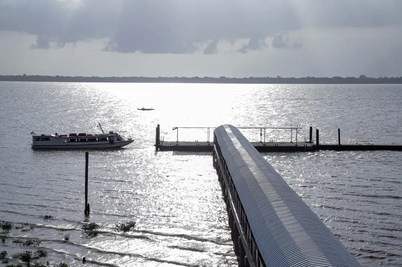 Passageiros aguardam embarque no Terminal Hidroviário de Belém, com barcas atracadas ao fundo.