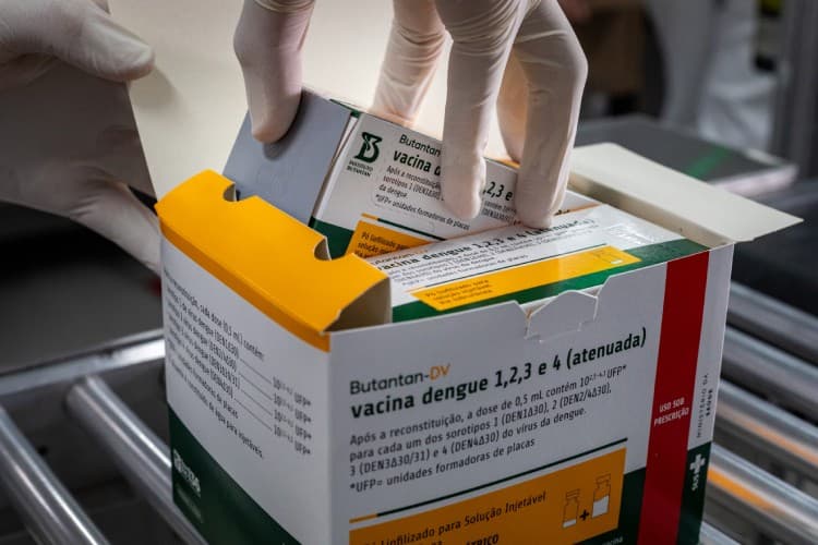 Profissional de saúde segura frasco de vacina em posto de vacinação no Acre.