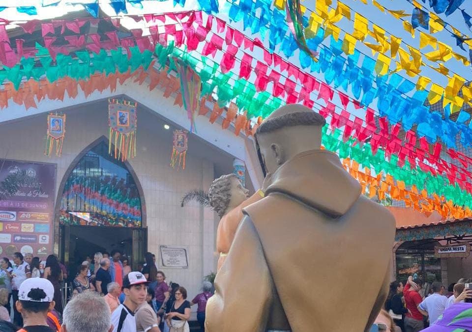 Fieis rezam em frente à paróquia iluminada durante noite de festa em Ananindeua.