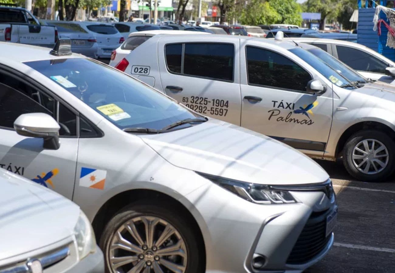 Fila de táxis aguardando passageiros em ponto central de Palmas, ao lado de placa de sinalização.